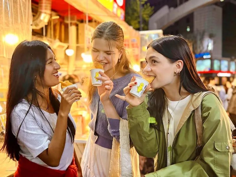 Visitors tasting at a glowing night market beside an illuminated palace on a seoul food tours evening tour in Seoul, South Korea
